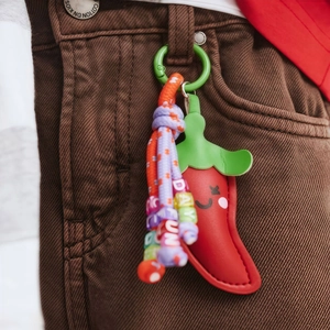 Red chili pepper keychain with colorful braided rope and letter beads on brown corduroy