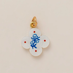 Détail d'un pendentif trèfle en émail blanc avec motifs floraux et placage en or 18K