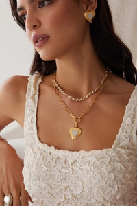 Detail of layered heart necklace with gold chain and pearl earrings on model