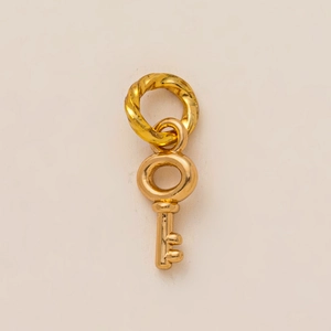 Gros plan d'un pendentif clé dorée au fini poli avec une bélière torsadée de style vintage