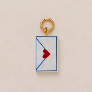 Détail macro du pendentif enveloppe avec coeur rouge et anneau doré plaqué 18K