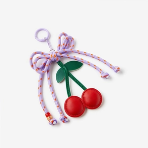 Detailed view of handmade leather cherry keychain with purple floral bow and green leaves