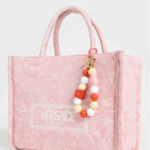 Close-up of pink floral canvas tote with brand logo patch and colorful beaded tassel charm
