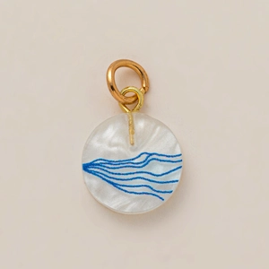 Détail du pendentif rond nacré avec motifs de vagues bleues et anneaux dorés 18 carats