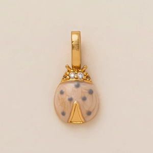 Détail macro d'un pendentif coccinelle en émail beige avec des yeux en cristal doré