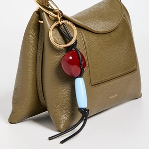 Detail of olive green lychee grain leather bag with beaded tassel and gold branding
