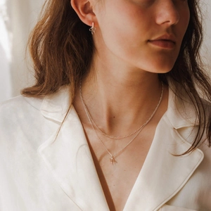 Dettaglio della collana con fiocco in argento e orecchini coordinati su modella
