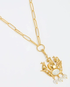 Detailed view of a golden sailboat pendant with white pearl and moonstone on a paperclip chain