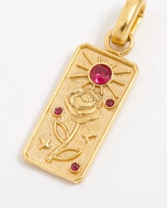 Detailed macro view of 14k gold rectangular rose pendant with red zircon stones