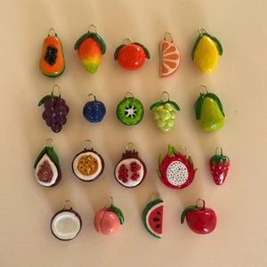 Detailed collection of assorted realistic fruit pendants with golden loops on a beige background