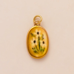 Macro detail of oval pendant with yellow enamel finish and white floral patterns
