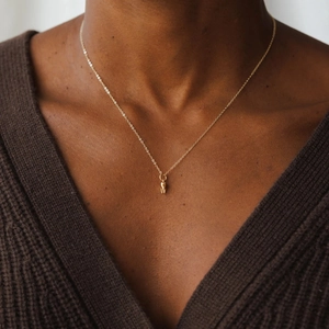 Collana minimalista dorata con un piccolo ciondolo a forma di dente su catena sottile