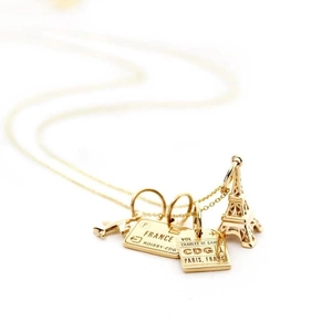 Detailed close-up of golden necklace charms featuring Eiffel Tower and Paris airport tags