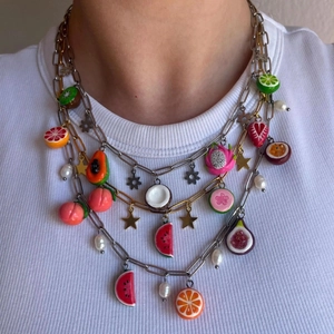 Detailed layered necklace showing colorful fruit charms and metallic stars on chains