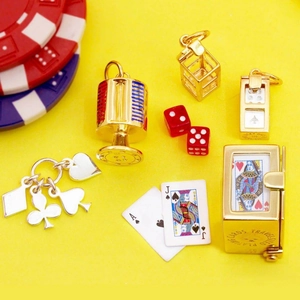 Macro shot of gaming pendants including lucky dice and mini playing cards on yellow background