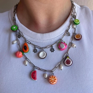 Detail of layered stainless steel necklace featuring colorful fruit charms and pearls