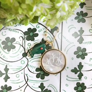Golden Libra necklace with malachite fish and white shell zodiac charms on floral background