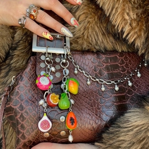 Colorful resin fruit bag charms with metal chains on a brown crocodile texture handbag