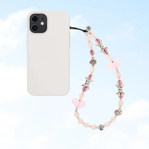 Close-up of a Y2K pink heart and silver thorn bead phone charm against a blue sky