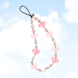 Pink heart beaded phone strap with metal tag against a clear blue sky and clouds