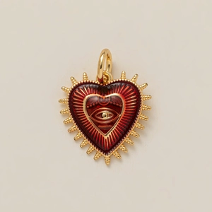 Detail of vintage heart pendant with red enamel evil eye and golden metal sunburst spikes