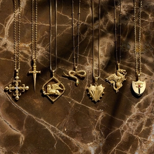 Vintage Goldketten-Set mit Schlangen-, Schwert- und Herzanhängern auf Marmorhintergrund