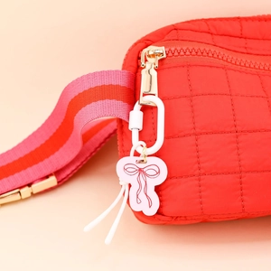 Detail der roten gesteppten Tasche mit rosa Schleifenanhänger und Streifengurt