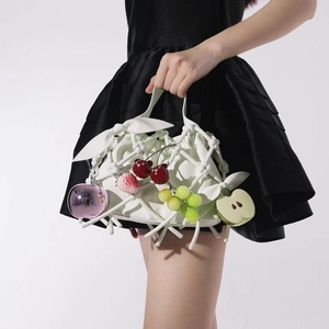 Bolso de mano blanco con estructura trenzada y colgantes de frutas coloridos