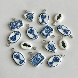 Detailed macro view of handcrafted ceramic cherry and nautical pendants with metal loops