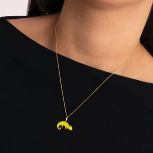 Primer plano de modelo con cadena dorada y colgante de camaleón en esmalte color amarillo