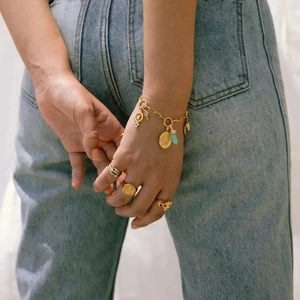 Nahaufnahme von goldenen Boho-Armbändern und Vintage-Münzringen an einer Hand