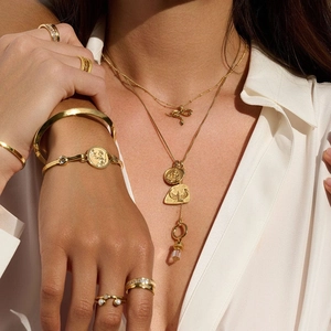 Mehrlagige Goldketten mit Schlangenanhänger und Münzen sowie passende Ringe am Model