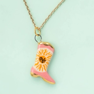 Detail of pink boot pendant with sun face pattern and golden metal chain necklace