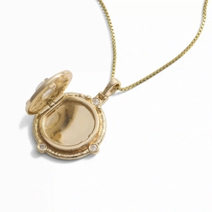 Detail eines Vintage-Goldmedaillons mit drei Kristallen und aufklappbarem Rundanhänger