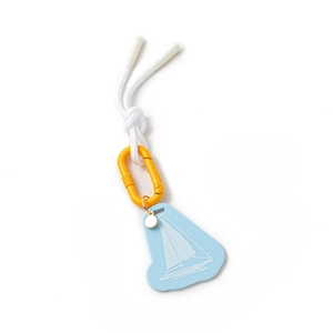 Detail of nautical keychain featuring light blue sailboat pendant and orange climbing buckle