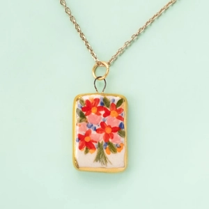 Detail of floral hand-painted ceramic pendant with colorful flowers and gold frame