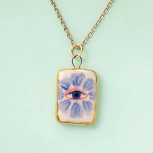 Macro shot of rectangular enamel evil eye pendant necklace with light blue floral textures