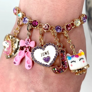 Close-up of a personalized bracelet featuring colorful charms like a unicorn and ballet shoes