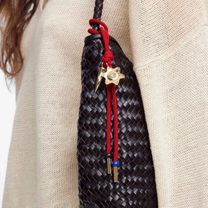 Deep brown woven leather bag featuring a red charm with gold star and blue bead