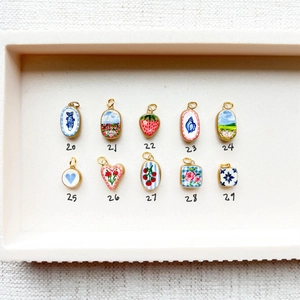 Vue détaillée de dix pendentifs colorés peints à la main avec motifs de fleurs et de fruits