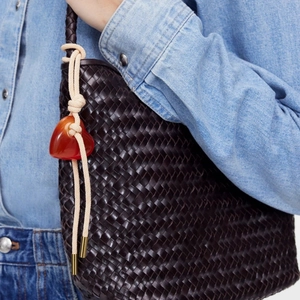 Deep brown woven tote bag with a red heart charm against blue denim clothing