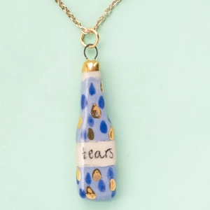 Detailed macro of a teardrop-shaped ceramic bottle pendant with blue artistic motifs
