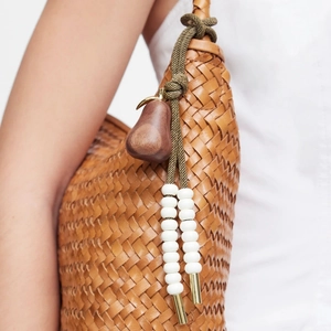 Handcrafted woven leather bag with wood pear charm and bead accents on model shoulder