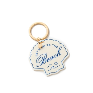 Detailed close-up of shell keychain with Let's Go To The Beach print and gold metal ring