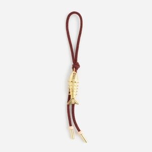 Detailed view of an articulated golden metal fish pendant on a deep red braided cord