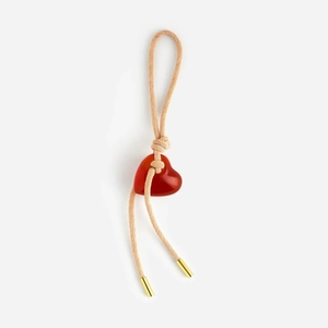 Detail of red heart gemstone pendant with beige braided cord and gold metal tips