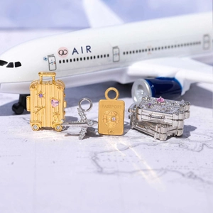 Set di ciondoli da viaggio con valigia dorata, passaporto e pendente aereo in argento