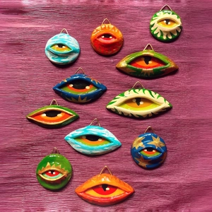 Hand-painted 18K gold evil eye charms in assorted colors on vibrant purple background