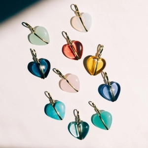 Detail van hartvormige hangers in diverse kleuren met gouden draadwikkeling