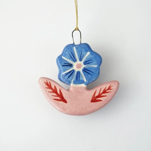 Vue macro d'un pendentif fleur en céramique bleue avec crochet plaqué or 18 carats